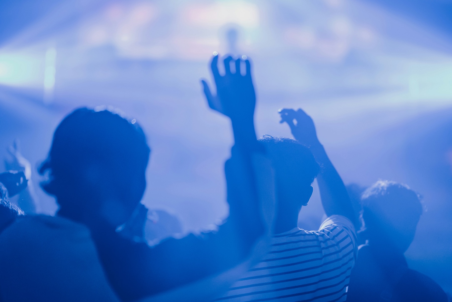 Crowd with hands raised in blue concert light
